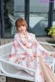 A woman sitting on a white bench wearing a white robe.