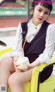 A woman sitting on top of a yellow car holding a coconut.