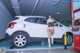 A woman standing next to a white car in a parking garage.