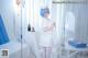 A woman dressed as a nurse standing in a hospital room.