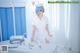 A woman in a white nurse outfit standing next to a table.