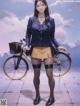 A woman in a school uniform standing next to a bicycle.