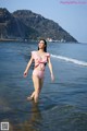 A woman in a pink bikini standing in the water.