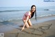 A woman in a pink bathing suit writing in the sand on the beach.