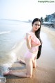 A woman in a pink bikini sitting on the beach.