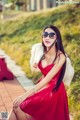 A woman in a red dress sitting on a bench.