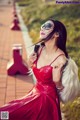 A woman in a red dress and sunglasses posing for a picture.