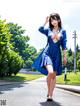 A woman in a blue dress is walking down the street.