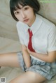 A woman in a school uniform sitting on the floor.