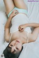 A woman laying on top of a white bed.