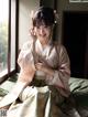 A woman in a pink kimono sitting on a bed.