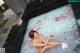 A naked woman sitting in a bathtub filled with rose petals.