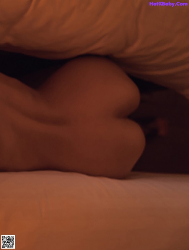 A person laying on a bed under a blanket.