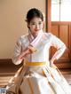 A woman in a white and pink hanbok is posing for a picture.