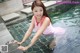 A woman in a pink dress is sitting in a pool.