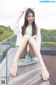 A woman sitting on a wooden deck with her legs crossed.