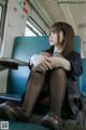 A woman sitting on a train with her legs crossed.