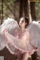 A woman in a pink dress with white angel wings.