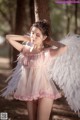 A woman in a pink dress with white angel wings.