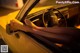 A woman's feet sticking out the window of a yellow car.