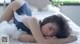 A woman laying on top of a bed covered in white fluffy material.