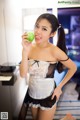 A woman in a maid outfit holding an apple.