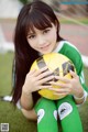 A young woman holding a soccer ball on a field.