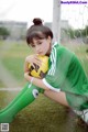 A woman sitting on the ground holding a soccer ball.