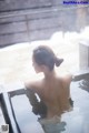 A woman in a white dress is sitting in a hot tub.