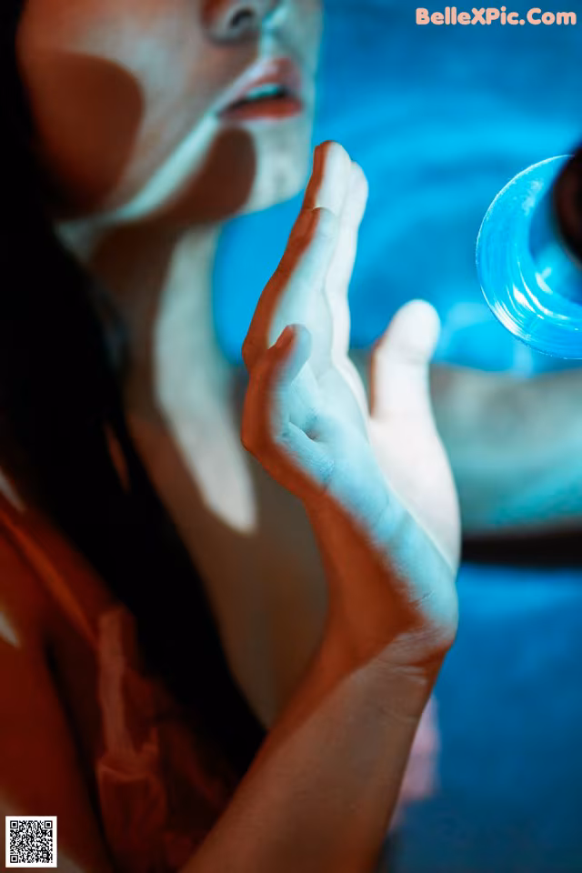 A woman holding a glass of water in her hand.