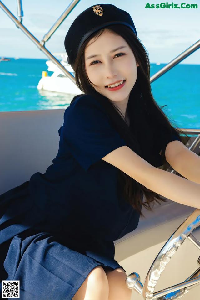 A woman sitting on the steering wheel of a boat.