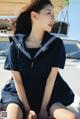 A woman in a sailor outfit sitting on a boat.