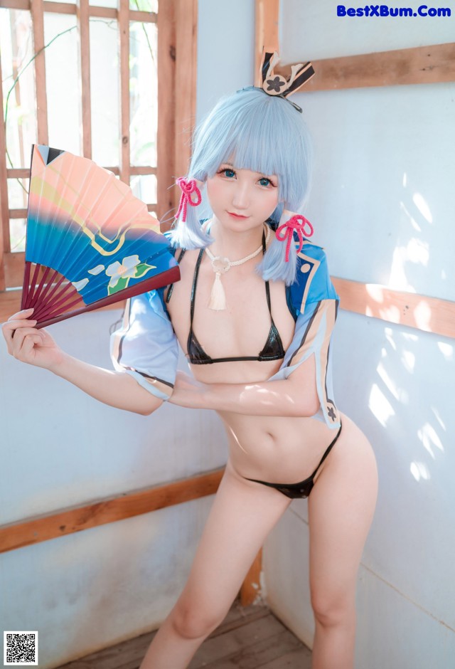 A woman in a bikini holding a fan.