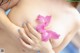 A woman holding a pink flower in her breasts.