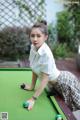 A woman leaning over a pool table with a ball.