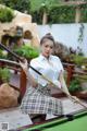 A woman in a skirt and shirt holding a pool cue.