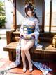 A woman in a kimono sitting on a wooden bench.