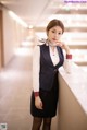 A woman in a business suit leaning against a wall.