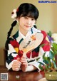 A woman in a kimono sitting at a table holding a fan.