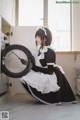 A woman in a maid outfit holding a washing machine.