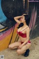 A woman in a red bikini posing in front of a graffiti wall.