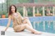 A woman sitting on the edge of a swimming pool.