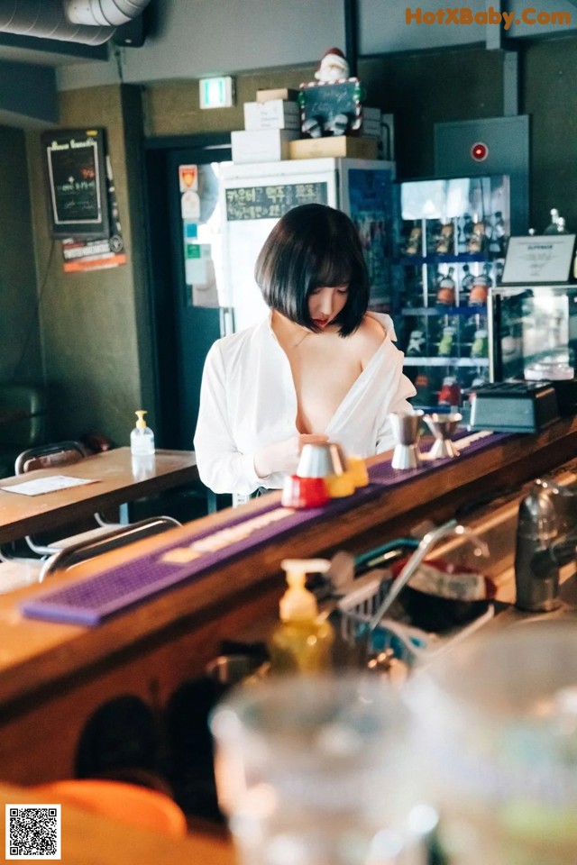 A woman standing behind a bar in a restaurant.