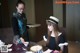 A waitress serving a woman a cup of tea at a table.