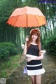 A woman in a black and white dress holding an orange umbrella.