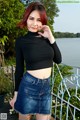 A woman in a black top and a denim skirt posing for the camera.