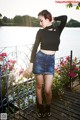 A woman standing on a wooden deck next to a body of water.