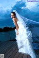 A woman in a wedding dress standing on a dock.