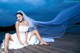 A woman in a wedding dress sitting on a dock.