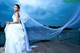 A woman in a wedding dress standing on a dock.